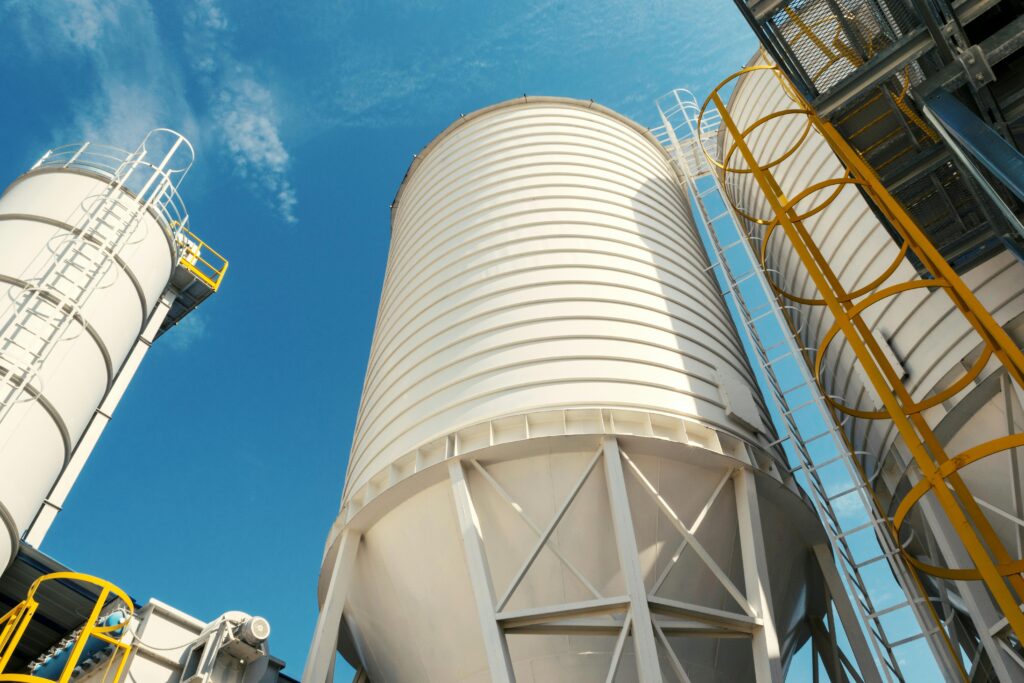 Wide-angle view of industrial silos with clear blue sky, captured during daytime, showcasing modern industry.